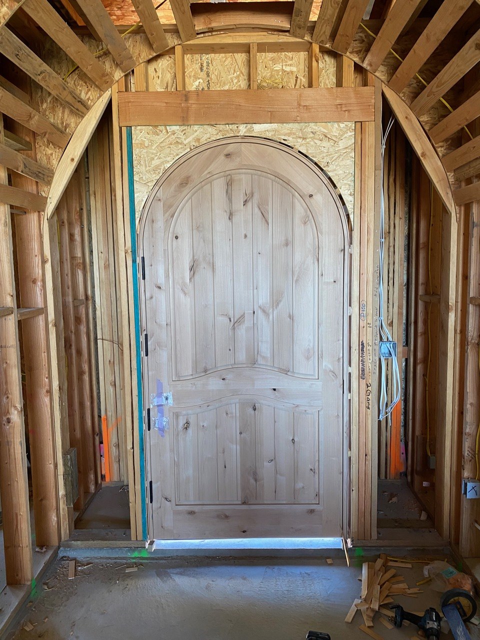 Custom arched knotty-alder entry door set into a framed radius opening