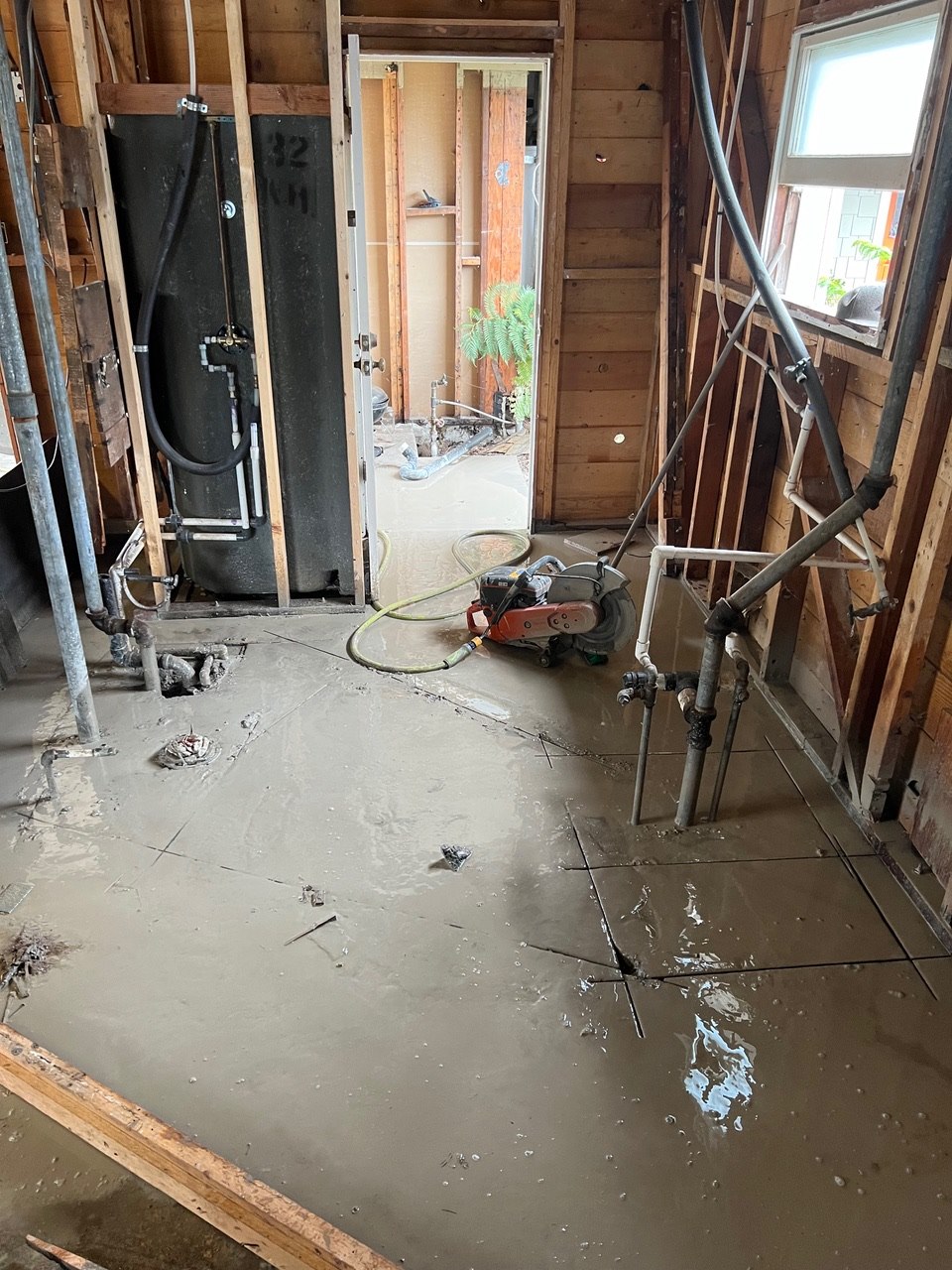 Bathroom remodel in progress with concrete slab cut for new plumbing