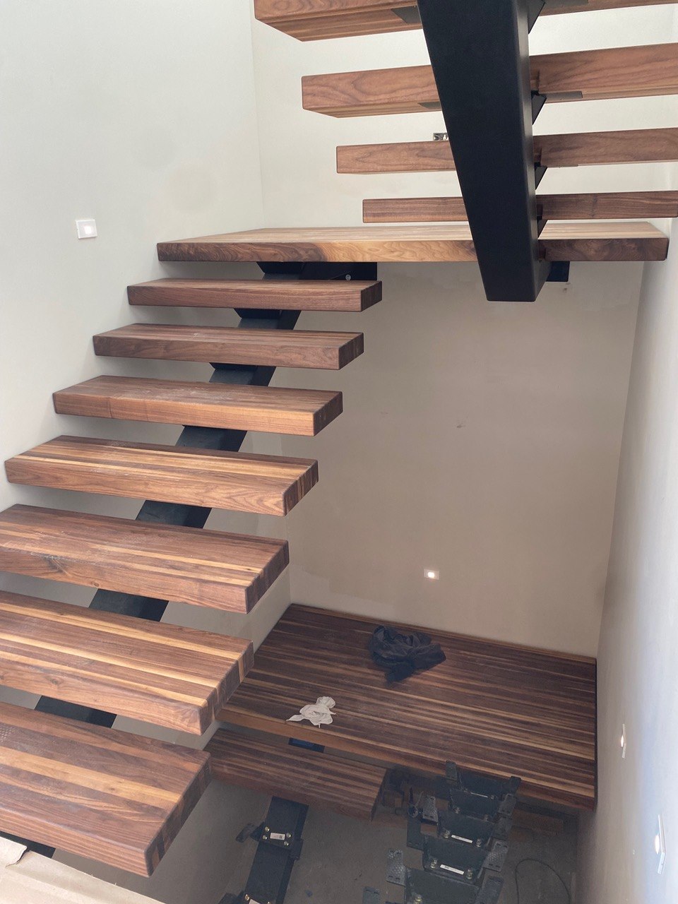 Custom cantilevered floating staircase in solid walnut with a steel spine